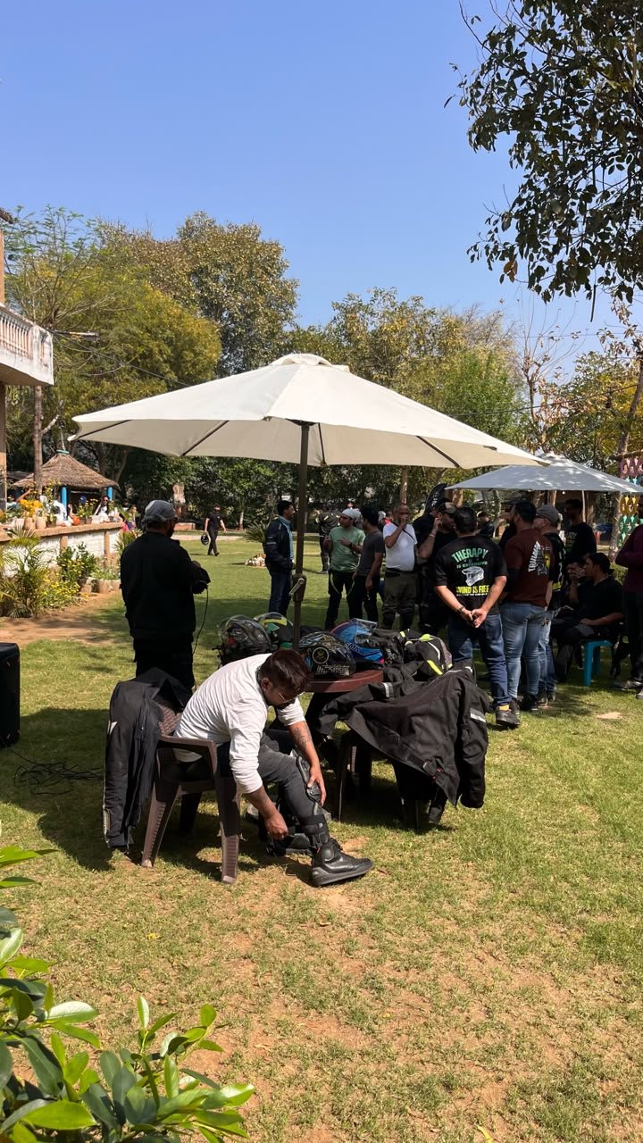 A cup of chai held up against the camp gardens